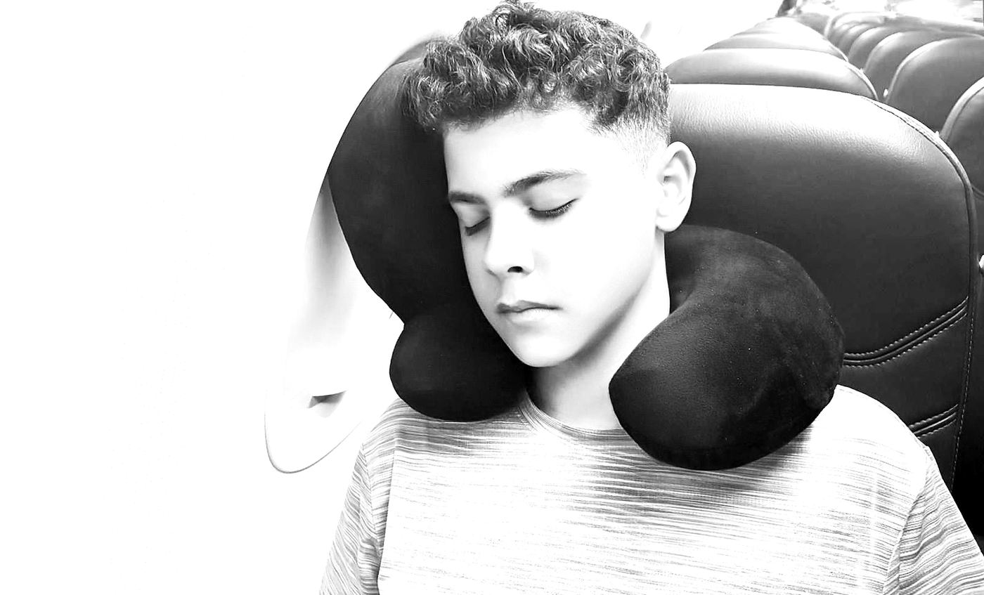 Young traveller sleeping comfortably with Nap-Star 2-in-1 neck and head travel pillow
